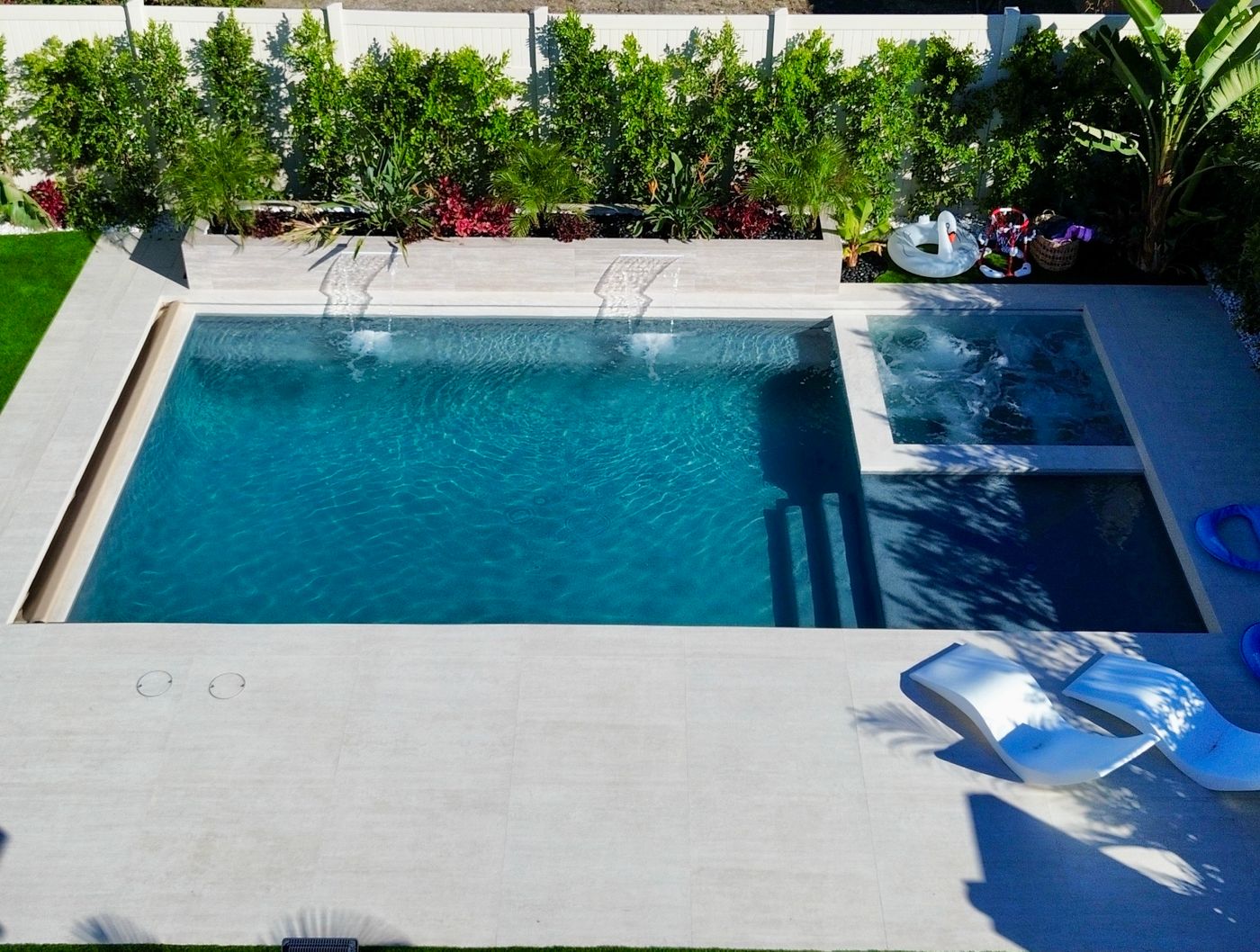 Rectangular pool, Baja shelf, and spa in Woodland Hills with porcelain decking.
