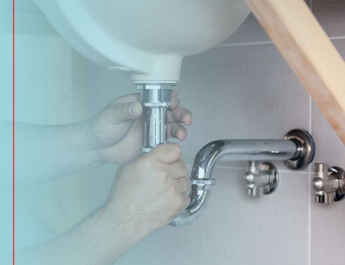 plumber looking at a pipe under a sink