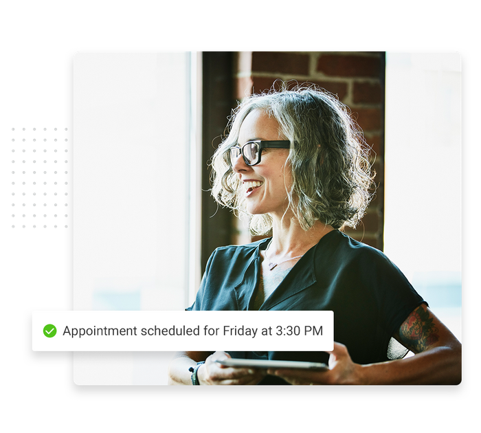 Smiling woman with glasses overlaid with a checkmark that says 'Appointment scheduled for Friday at 3:30 PM' scheduling software for small business