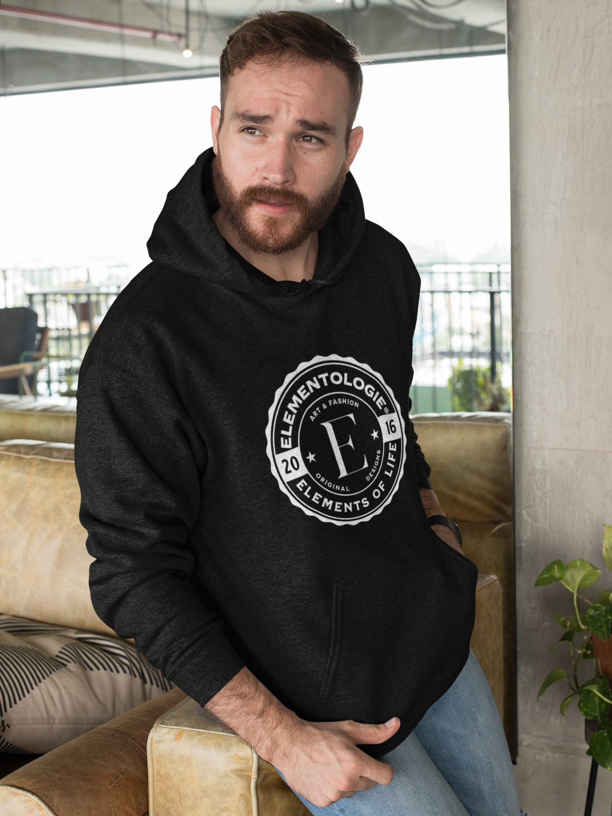 pullover-hoodie-mockup-featuring-a-bearded-man-leaning-over-a-sofa-28741 (2).png