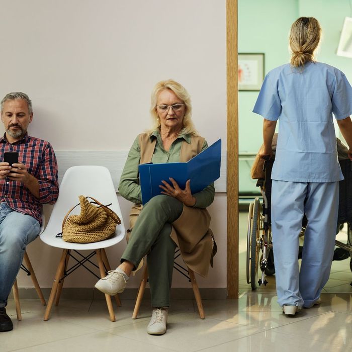 Man and woman sitting in a waiting room while a nurse wheels a patient into the back