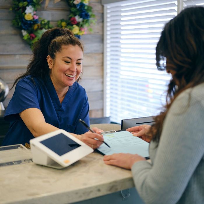 Nurse helping patient fill out paperwork at front desk