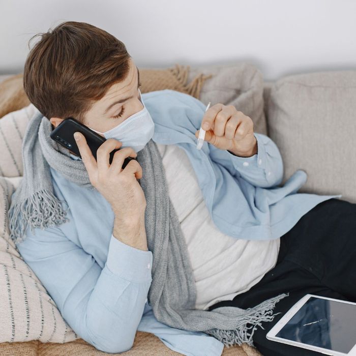 a person on a phone looking at a thermometer The Benefits of a Virtual Doctor Visit (2).jpg