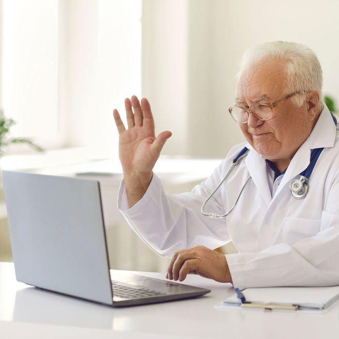 a doctor waving at a laptop camera The Benefits of a Virtual Doctor Visit.jpg