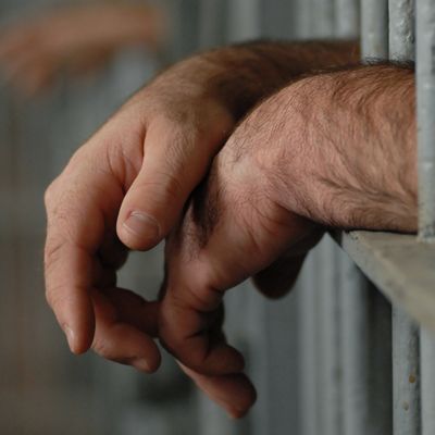 Image of a man's hands resting on jail bars