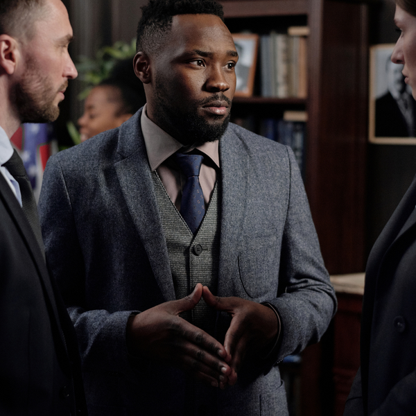 Two men and a woman wearing suits having a discussion