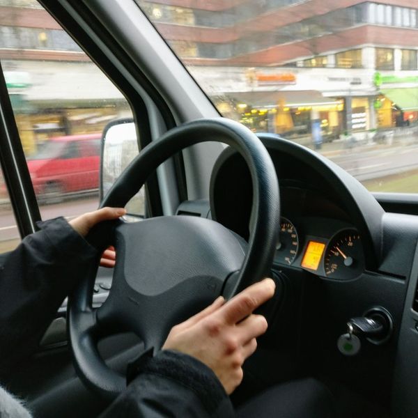 Driver’s hands on the steering wheel while driving a car.