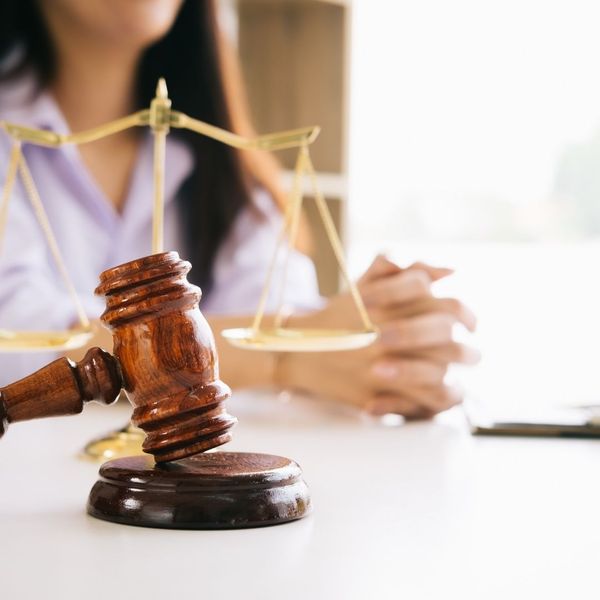 Wooden gavel and brass scales of justice resting on an office desk.