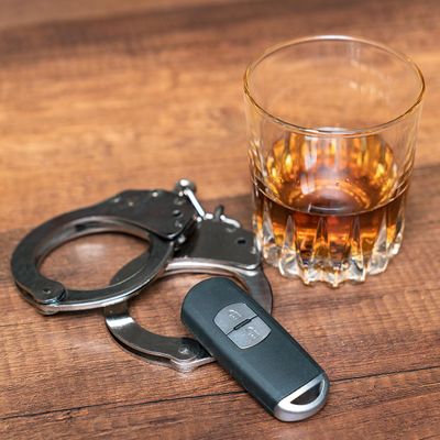 Handcuffs, car key and a glass of alcohol