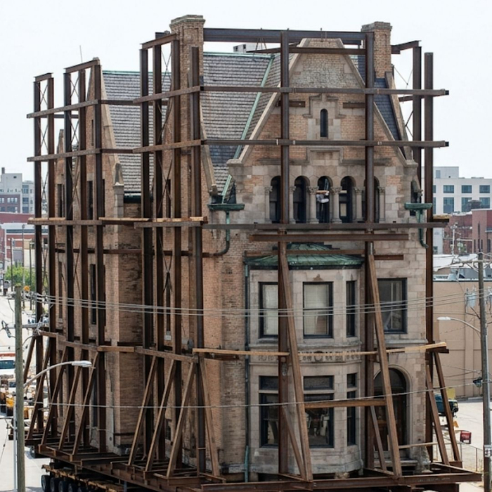 Historic brick landmark building being relocated down city street.