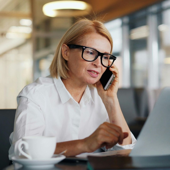 woman using phone and laptop to make insurance claim