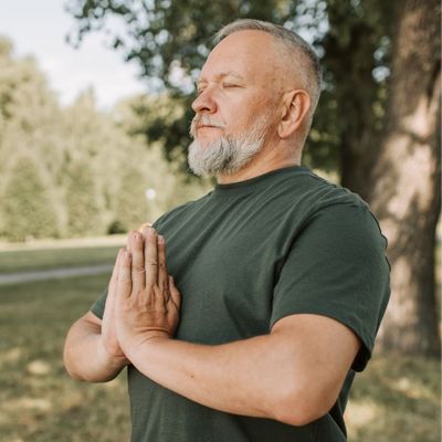 fit middle-aged man doing yoga outdoors