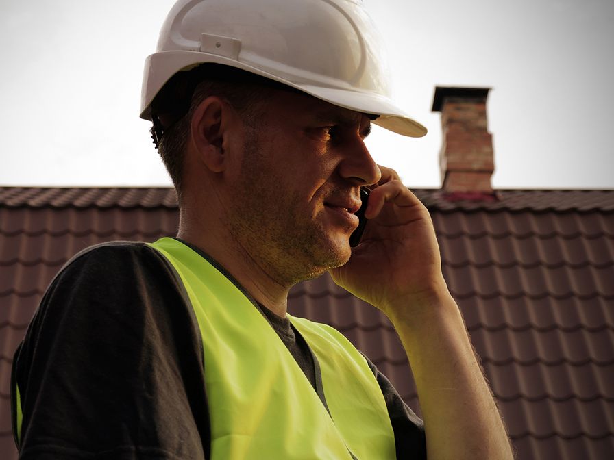 image of roofing contractor in hard hat on mobile phone