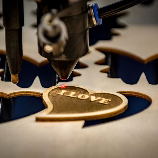 laser cutting wood in shape of hard with the words I Love