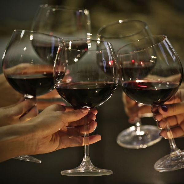 clinking together wine glasses filled with red wine