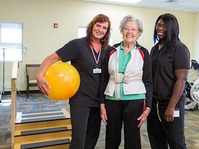 Nurses and patient in gym doing physical therapy