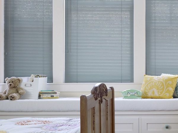 a bedroom window with a comfortable window seat covered in sleek, silver aluminum blinds.