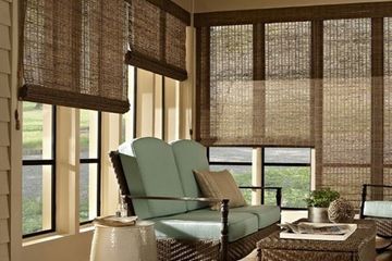 a sunroom with large windows featuring natural woven shades and comfortable seating.