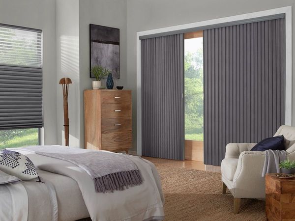 a modern bedroom with a large bed and gray honeycomb shades on the window and sliding vertical shades on the glass door. a modern bedroom with a large bed and gray honeycomb shades on the window and sliding vertical shades on the glass door.