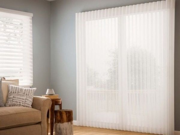 a living room with a couch and large windows covered by sheer, light-filtering window shadings. a living room with a couch and large windows covered by sheer, light-filtering window shadings.