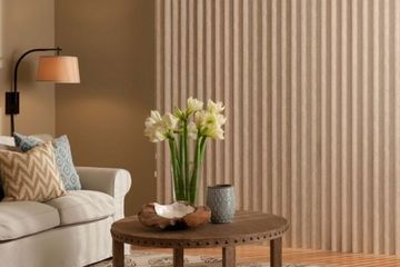 a living area with a sofa and vertical shades in a neutral tone covering a large window.