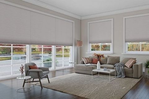 a living room with large windows covered in neutral-colored roller shades, showing off a modern and clean design.
