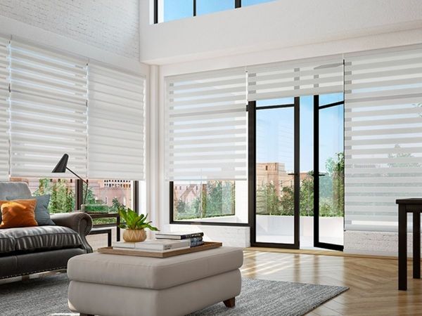 a spacious, modern living room with large windows covered in white dual shades with alternating sheer and solid stripes. a spacious, modern living room with large windows covered in white dual shades with alternating sheer and solid stripes.