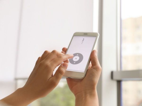 a person using a smartphone to control automated blinds, with the app showing up/down directional controls. a person using a smartphone to control automated blinds, with the app showing up/down directional controls.