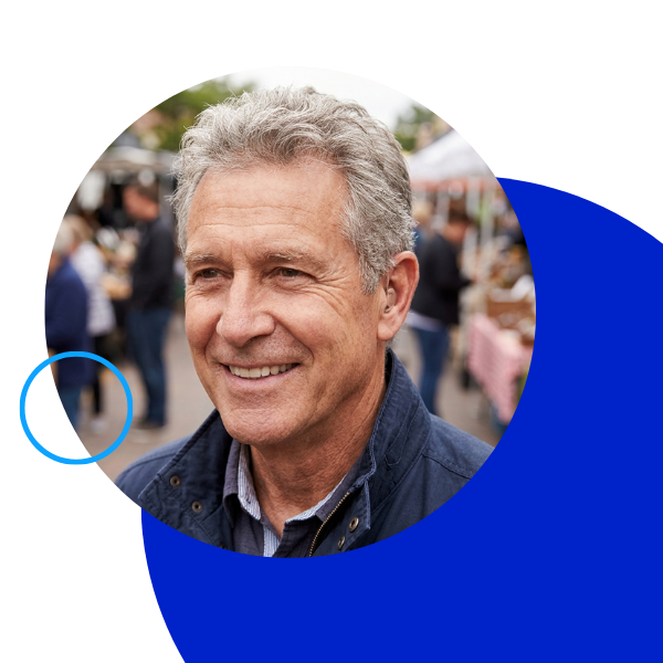 Smiling mature man wearing a discreet hearing device outdoors.