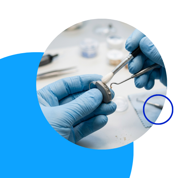 Close up of specialist hands carefully cleaning a small electronic device with tools.