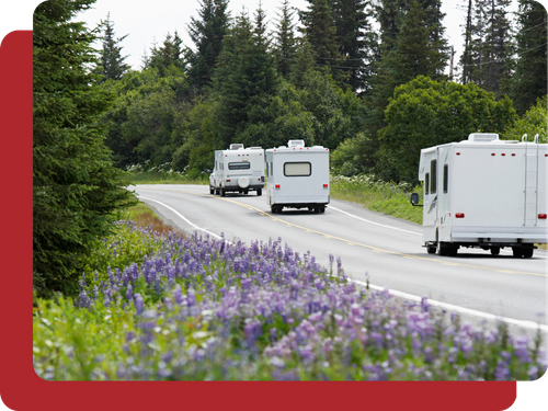 three different style RVs driving through a pretty forest scene