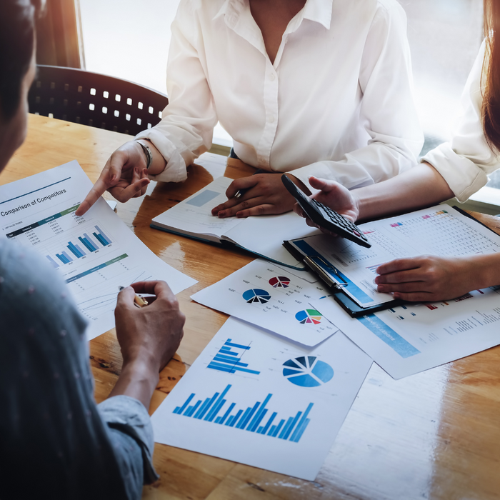 Three people analyzing financial documents. 