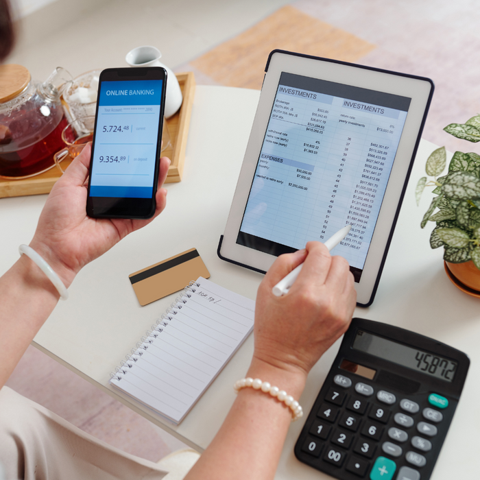 Person using a phone and tablet to look at financial documents. 