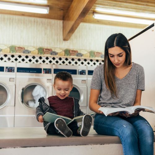 a woman and child reading in a laundromat