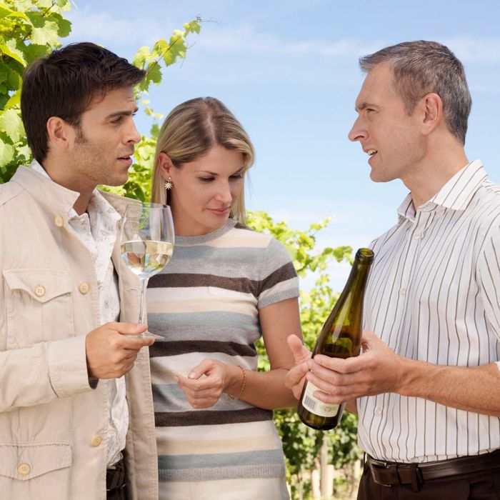 man talking to a couple about a wine bottle