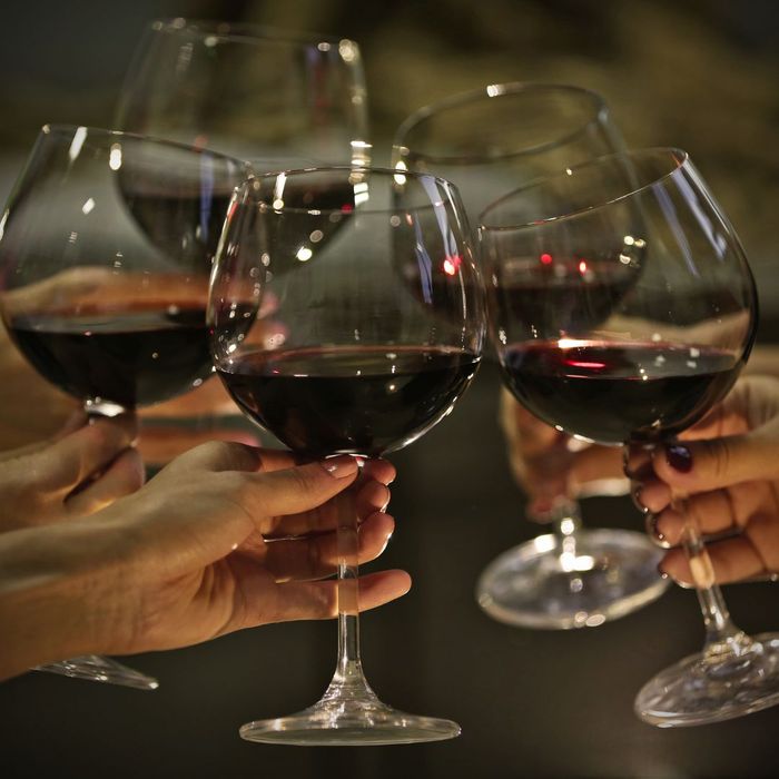 Five people in a circle clinking wine glasses together. 
