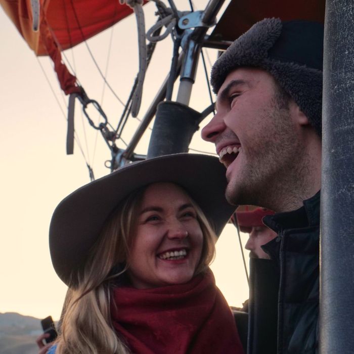 Man and a woman in a hot air balloon, laughing. 