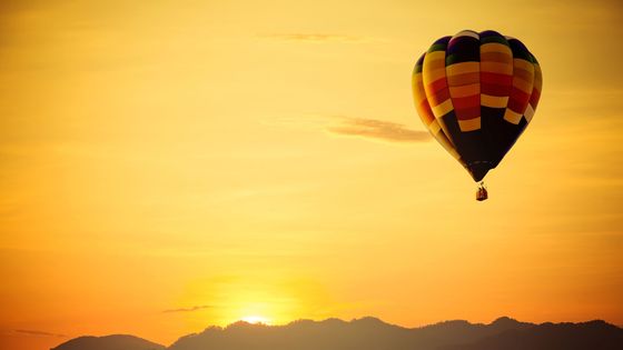 Hot air balloon rising up over the sunrise. 