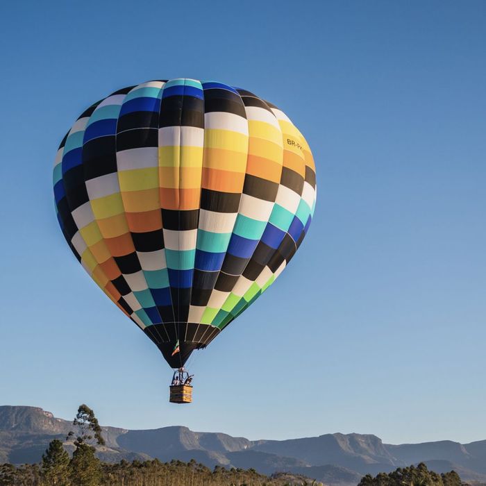 multi-colored hot air balloon floating through a blue cloudless sky