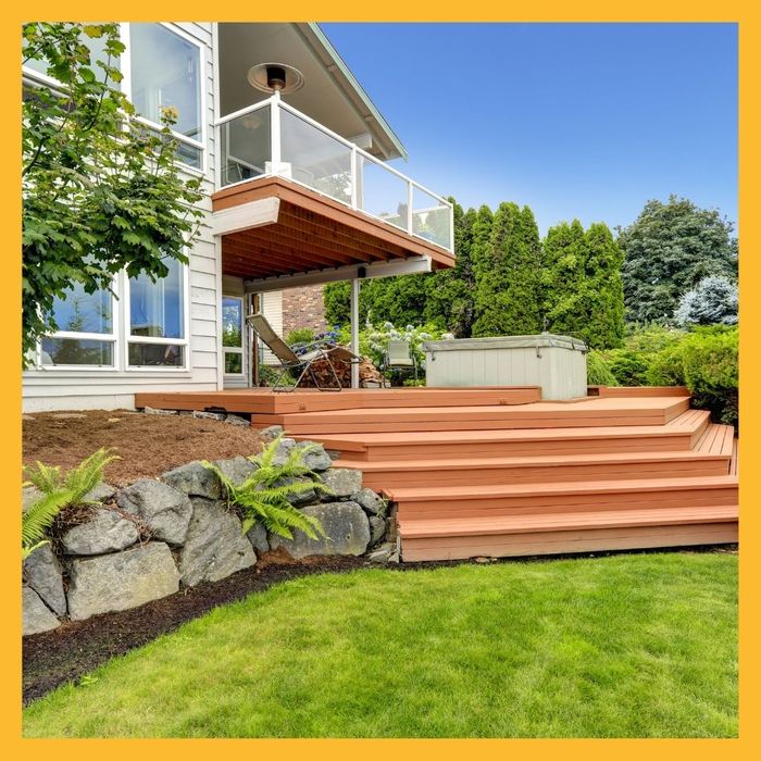 A nice deck with a hot tub in a well landscaped backyard. 