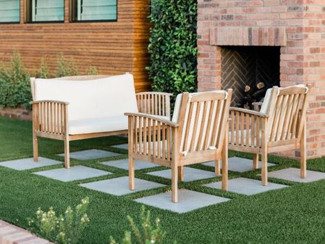 A yard with patio furniture sitting on paved landscaping with a brick fireplace in the background