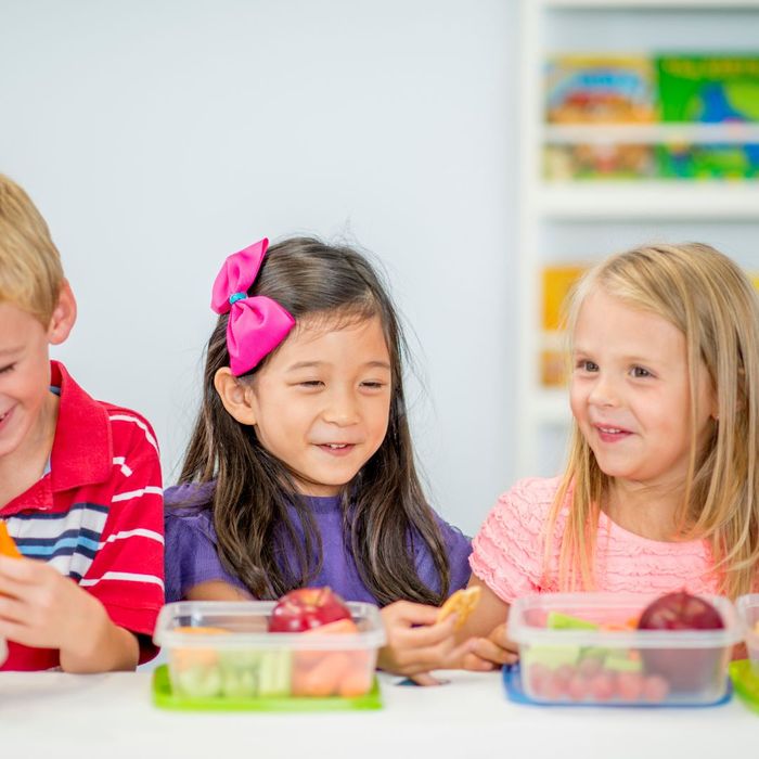 Young kids sitting together eating lunch.
