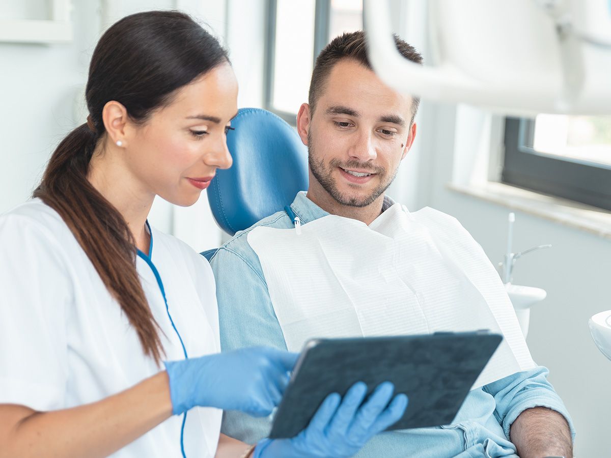 photo of female dentist looking over chart with patient