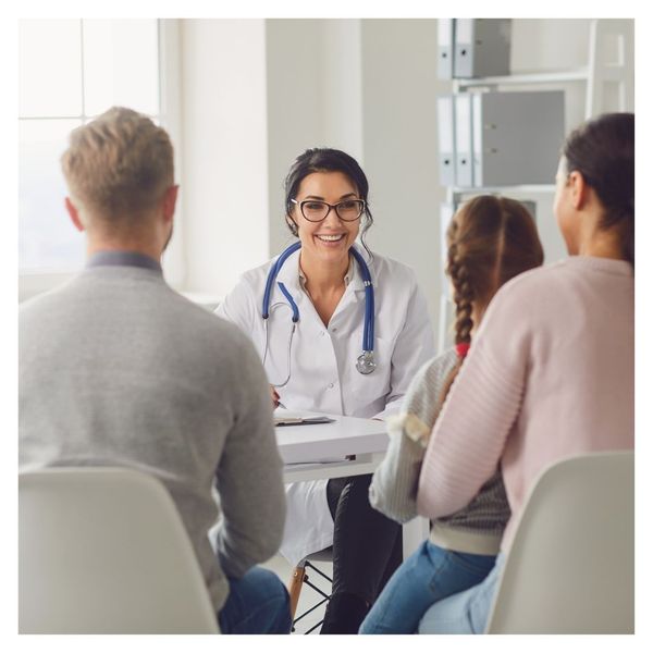 Smiling doctor sits with patients looking over document