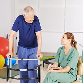 Male patient with walker and female physical therapist