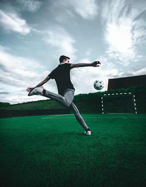 Man kicking soccer ball on turf field