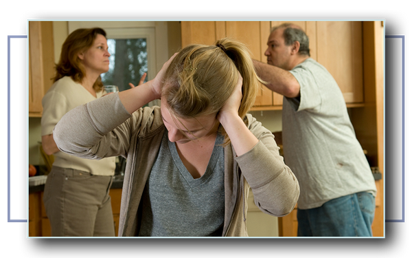 A young woman holds her hands to her head, looking upset as her parents argue behind her.