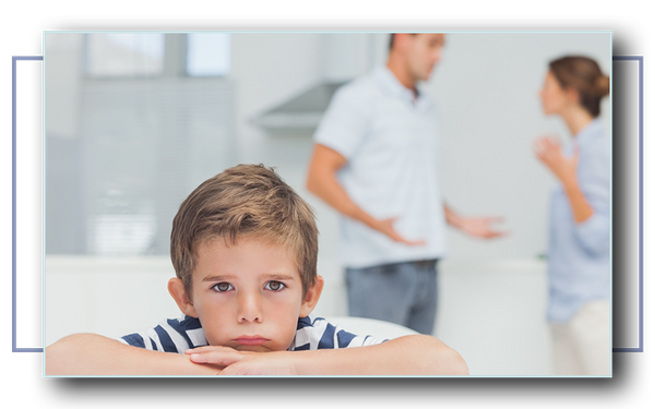 Sad boy with arms folded while parents quarreling in the kitchen.