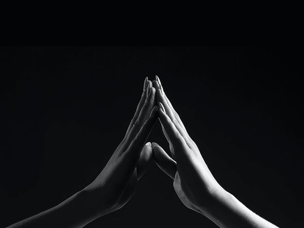 Black and white picture of two people touching the tips of their fingers together