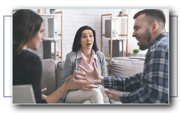 Amazed family therapist looking at mad couple arguing during marriage counseling session.